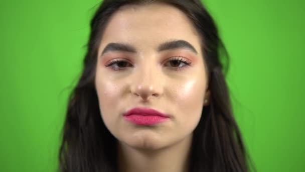 Schoonheid speels meisje zet roze kauwgom in de mond, eet snoep op groen scherm — Stockvideo