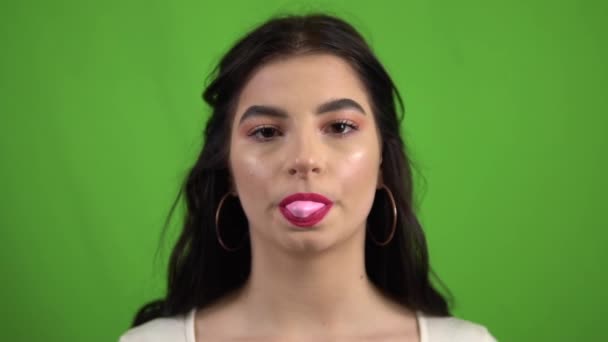 Sexy meisje blazen bubbels kauwgom kauwgom op groen scherm slow motion — Stockvideo