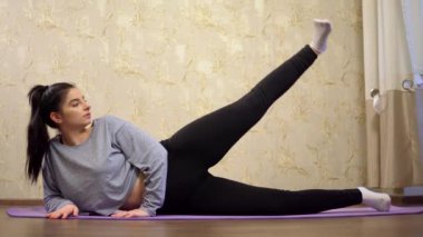 Evde spor yapan genç bir kadın, spor giyiminde kadın fitness eğitimi.