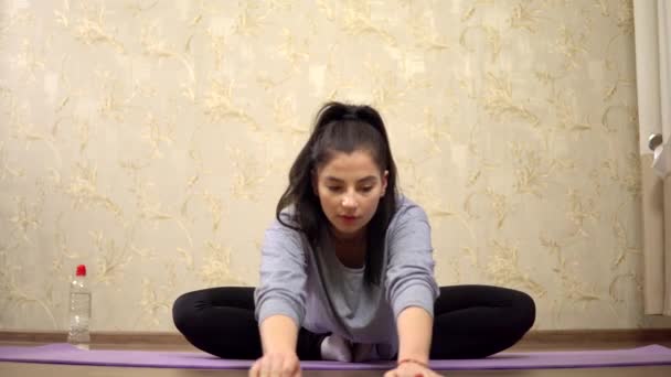 Genç kadın, esneme egzersizlerini bez yoga pratiği üzerinde yapmaya başlıyor. — Stok video