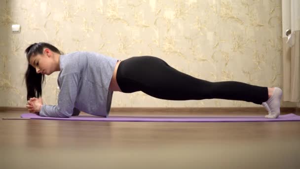 Evde spor yapan genç bir kadın, evde antrenman, yoga tahtası. — Stok video