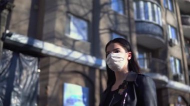 Koruyucu tıbbi maskeli bir kadın sokakta, karantinada, koronavirüste yürüyor.