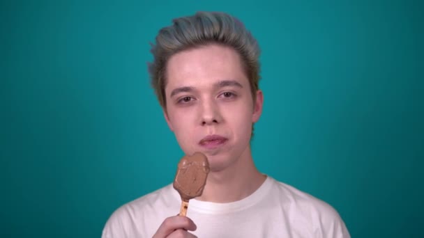 Jonge gelukkig man eten chocolade ijs op zoek naar camera portret — Stockvideo