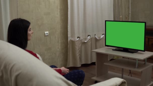 Mujer viendo televisión de pantalla verde en el sofá en la acogedora sala de estar relajante en casa — Vídeo de stock