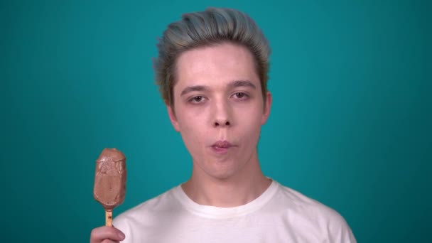 Mladý šťastný muž těší jíst čokoládovou zmrzlinu hledá fotoaparát portrét