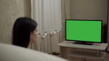Öksüren genç kadın, yeşil ekran maketi seyrediyor. Rahat evinde dinleniyor.