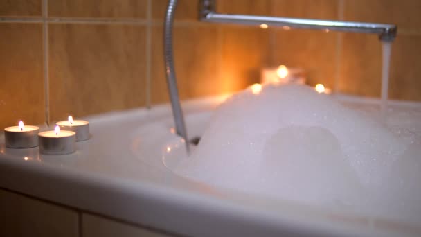 Babble bath with candles, hot water pours in bath, foam, romantic atmosphere — Stock Video