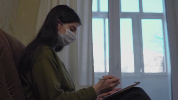 Woman in medical protective mask stay home draws painting sketchbook, quarantine — Stock Video