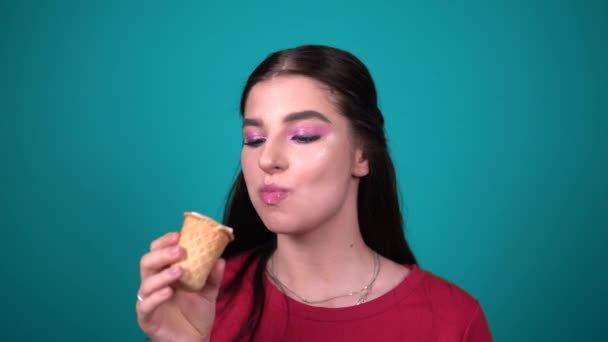 Joven mujer feliz comiendo helado disfrutando de dulces aislados sobre fondo azul — Vídeo de stock