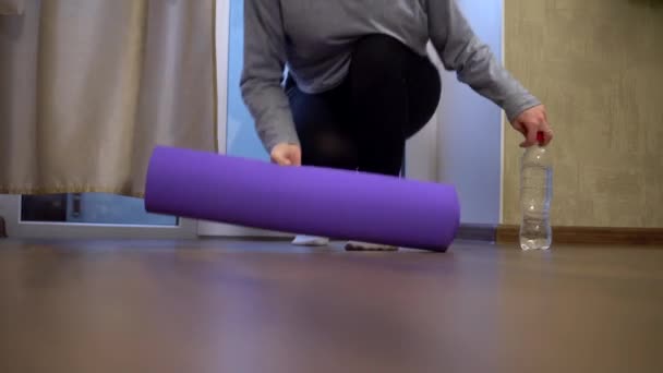 Stressgeplagte junge Frau breitet einen Teppich aus, um beim Sport Yoga zu praktizieren — Stockvideo