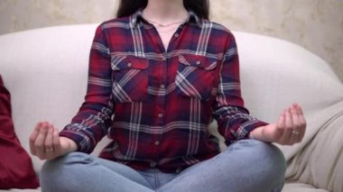Genç bir kadın rahat bir evde meditasyon yapıyor, dinleniyor, yoga nilüfer çiçeği pozu veriyor.