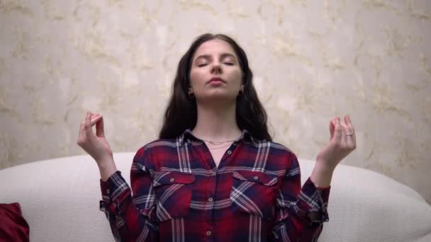 Молодая женщина медитирует в уютном доме, расслабляет, йога поза лотос — стоковое видео
