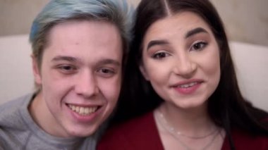 Çift yakın çekim televizyon seyrediyor. Gülüyorlar. Evdeki rahat atmosferde dinleniyorlar.