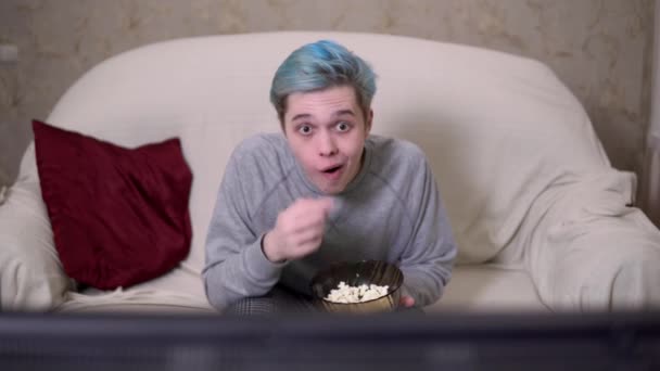 Человек сосредоточен на телевизоре или кино, ест попкорн, зомби, расслабляется дома — стоковое видео