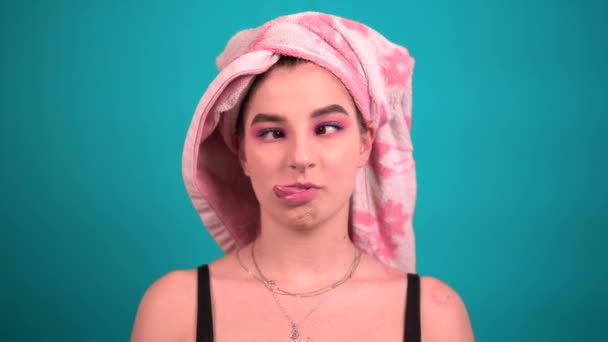 Legrační bláznivá mladá žena grimasy s ručníkem na hlavě, ukazující jazyk — Stock video