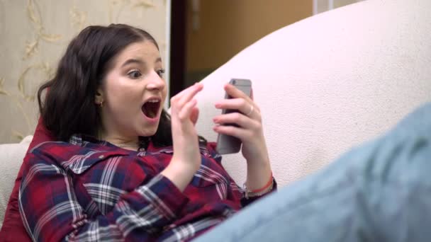 Mujer atractiva joven mirando la pantalla del teléfono, relajándose en casa, meditando — Vídeo de stock