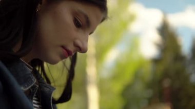 Şehir parkında dizüstü bilgisayarla çalışan genç bir kadın bankta oturuyor, serbest çalışıyor.