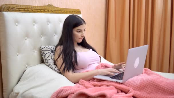 Mujer joven freelancer trabajando en la cama, acogedor hogar, utilizando el ordenador portátil en el dormitorio — Vídeo de stock