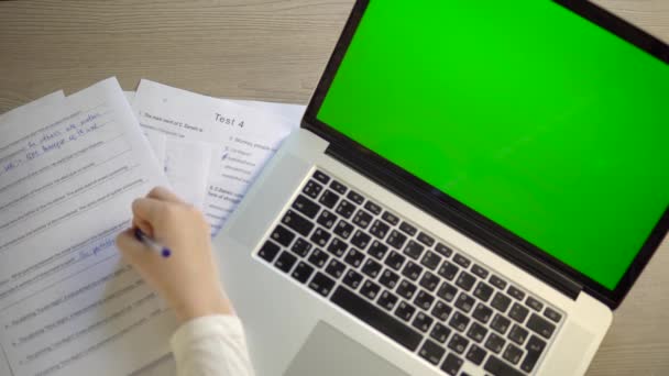 Laptop-Attrappe mit grünem Bildschirm, Papiere auf dem Schreibtisch, Studentin — Stockvideo
