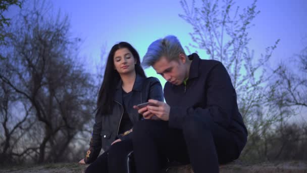 Fiatal férfi figyelmen kívül hagyja a barátnője játszik telefon a természetben, lány pihenni a természetben — Stock videók