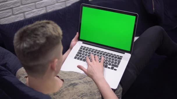 Mockup de la pantalla verde del ordenador portátil, hombre usando el ordenador portátil en el sofá en casa — Vídeos de Stock