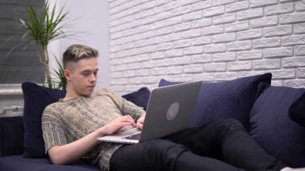 Aantrekkelijke glimlachende man met laptop, typen, freelancer werkafstand thuis — Stockvideo