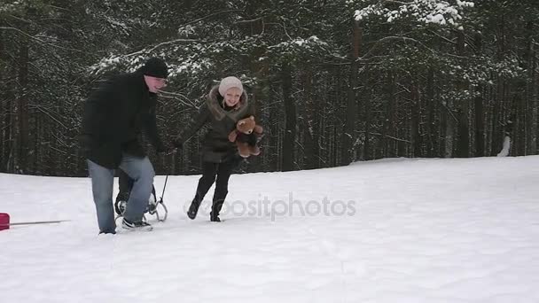 Родители бегают со своим ребенком на санях в зимнем парке 96fps — стоковое видео