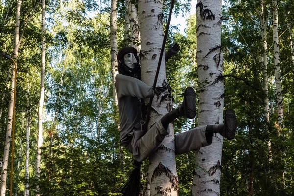 The character of Russian fairy tales Baba Yaga with a broom sits on a tree.