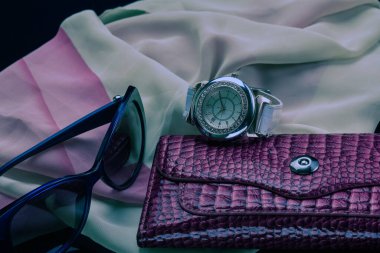 Saatler, gözlükler, çantalar başörtüsünün üzerinde yatıyor..