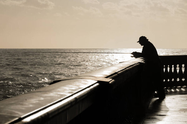 Silhouette of fisherman waiting his fish while the sun goes down
