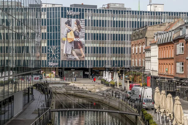 aarhus, Danimarka - 24 Mart 2020: Aarhus kasabasının şehir merkezinde Aarhus A nehri boyunca gezinme. Mağazalar ve ofisler her iki tarafta, Magasin Alışveriş Merkezi arka planda.
