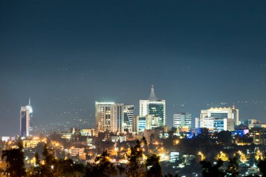A closeup view of Kigali city skyline lit up at night, under a deep blue evening sky clipart