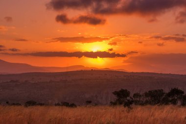 Güneş bulutların ardında yoğun bir günbatımında Afrika 'nın tepeleri, uçurumları ve savanaları üzerinde parıldıyor. Güney Afrika, Mpumalanga' daki Blyde Nehri Kanyonu 'nda.