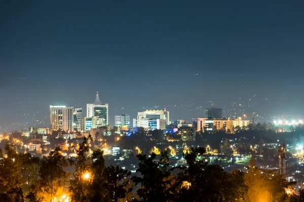 キガリ市内のスカイラインの広い景色は 前景に街路灯の輝きを持つ深い青色の夜空の下で夜にライトアップされます — ストック写真