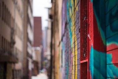 Johannesburg 'da renkli graffitilerle süslenmiş, ön plana odaklanmış ve uzaktaki bulanık bir şehrin soyut görüntüsü.