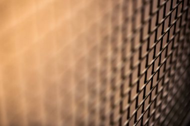 Çapraz çitlerle çevrili, daha aydınlık bir alanda gölgeye dönüşen yakın çekim, derin bir alan atışı.