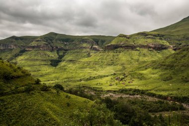 Dramatik bir gökyüzünün altındaki uçurum ve yamaçlar, Amfitiyatro dağının eteğindeki Tugela Vadisi yürüyüş rotası boyunca. Drakensberg, Güney Afrika