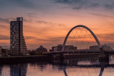 Glasgow / İskoçya - 20 Eylül 2016: Clyde Yayı ve çevresindeki binalar Clyde Nehri üzerinde turuncu bir günbatımına karşı