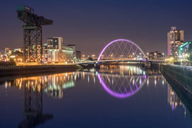 Glasgow / İskoçya - 20 Eylül 2016: Clyde Arc ve çevresindeki binalar gece Clyde Nehri 'ne yansıdı