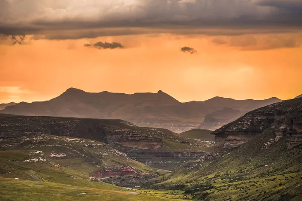 南アフリカのドラケンスバーグにあるゴールデンゲートハイランド国立公園から見られる アンフィシアター周辺のドラケンスバーグ山脈の上の黄金の夕日と嵐の雲の劇的なシーン — ストック写真