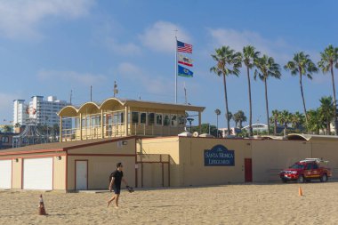 Santa Monica Plajı (Los Angeles), somut bir şekilde cankurtaran binasına yakın yürüyen bir kişi var..