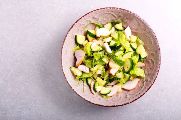 Салат из огурцов, салата и куриной грудки в тарелке — стоковое фото