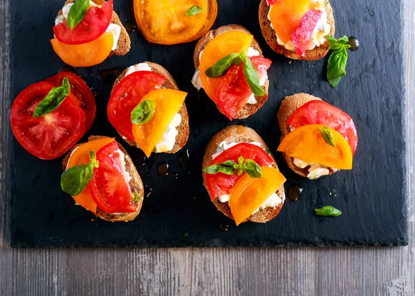 Сыр и томаты с брускеттой на черной доске — стоковое фото