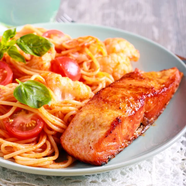 Жареная форель и спагетти на тарелке — стоковое фото
