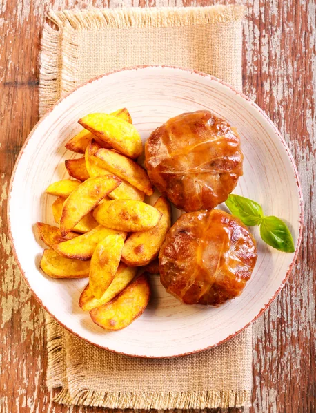 Beefsteaks wrapped in bacon and roast potato — Stock Photo, Image