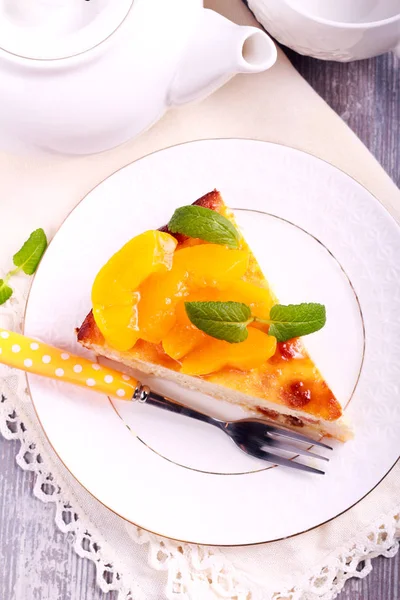 Slice of cheesecake with peach on top, on plate — Stock Photo, Image