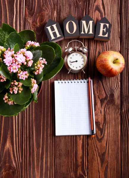 Vue du dessus du carnet à côté de la fleur, pomme, horloge et signe de la maison — Photo