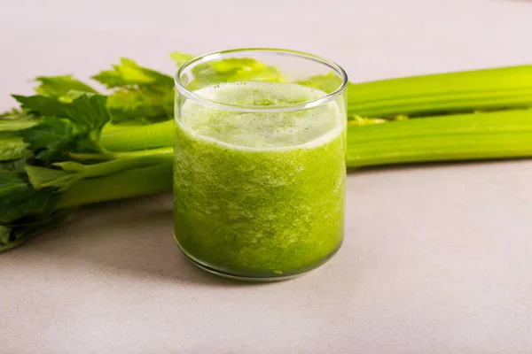 Celery smoothie in glass and celery stalks