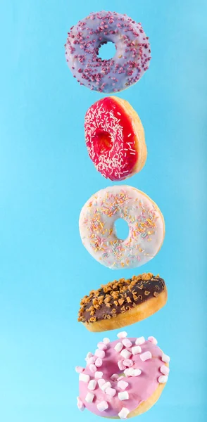 Flying donuts with colorful glaze over blue background — Stock Photo, Image