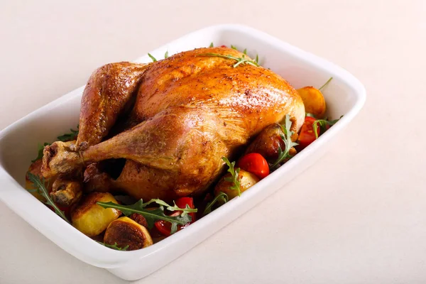 Roast chicken in a baking tin, on table